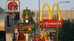 67bf566dbceca_fast food 1 A bunch of signs that are on the side of a building