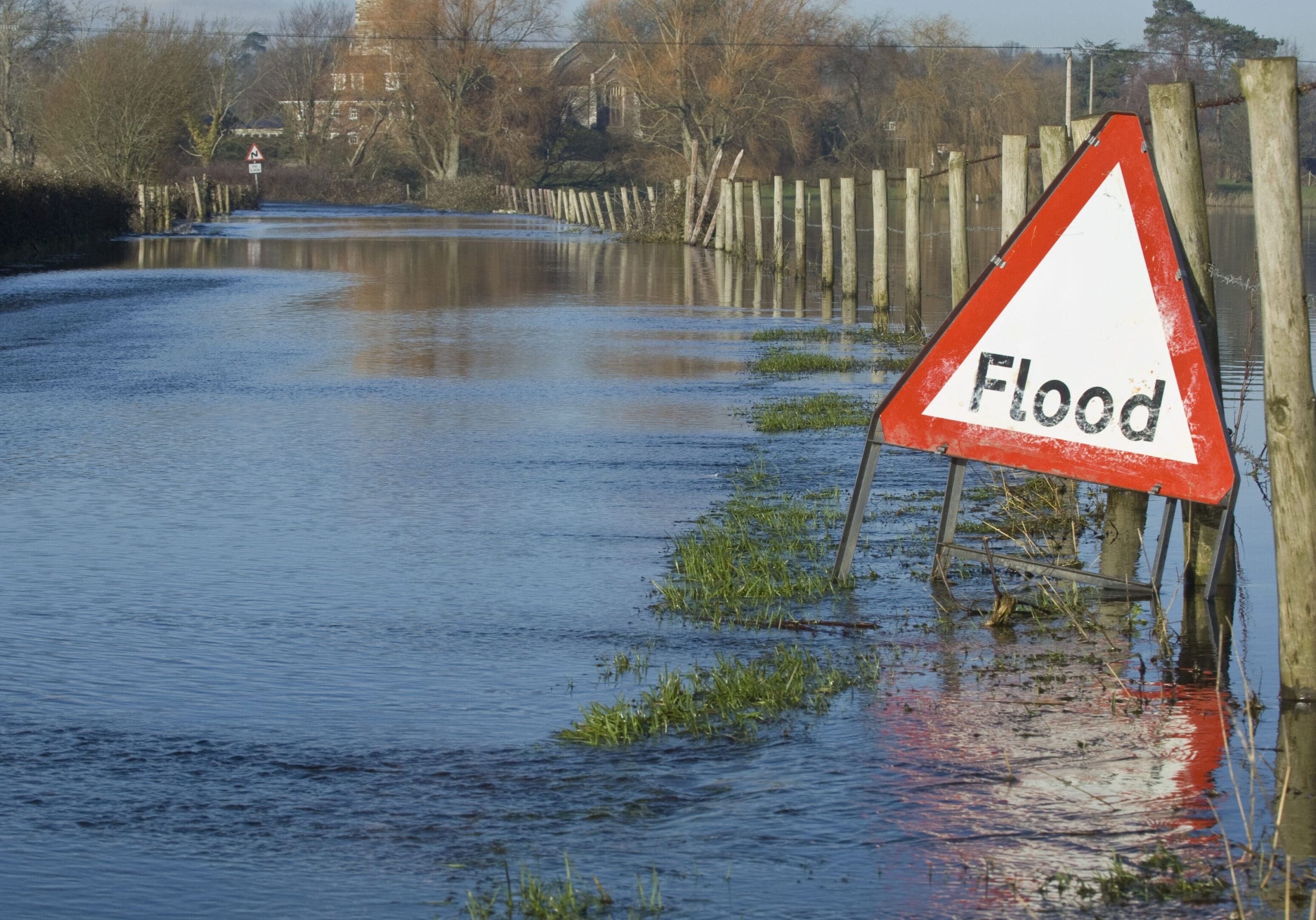 Flooded road and fields A flooded street with a sign warning of flooding.